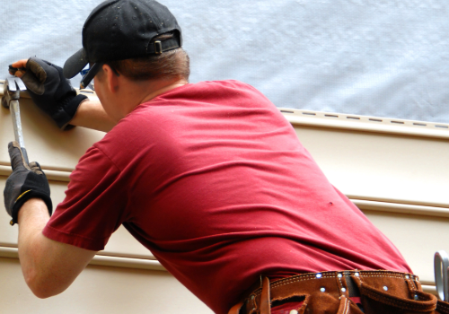 Expert Siding Installation by Story Roofing Professional installer in a red shirt and cap working on exterior home siding.