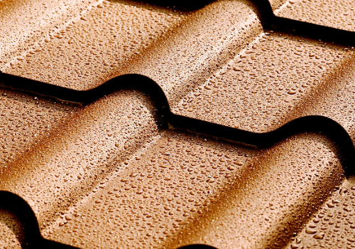 Steel Shingles Roofing by Story Roofing Close-up of wet steel shingles with droplets, showcasing the texture and quality.