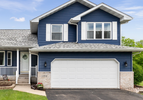 Expert Residential Roof Repairs by Story Roofing Newly repaired residential roof on a modern two-story home with a white garage door and lush front yard